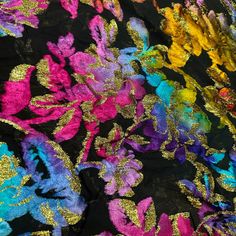 colorful fabric with gold and purple flowers on black background, closeup view from above