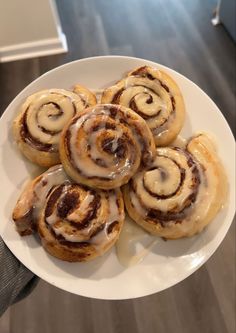 a white plate topped with cinnamon rolls covered in icing