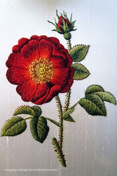 a red rose with green leaves on a white background is embroidered onto the side of a piece of fabric