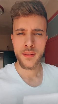 a close up of a person wearing a white t - shirt and looking at the camera