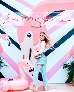 a woman standing in front of a flamingo wall