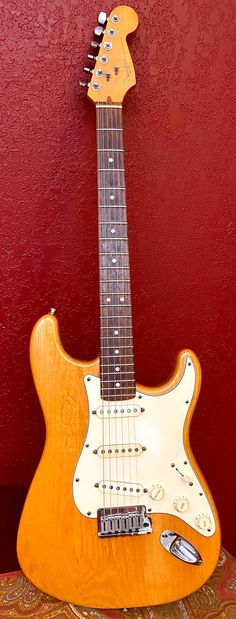 an electric guitar sitting on top of a table next to a red wall and carpet