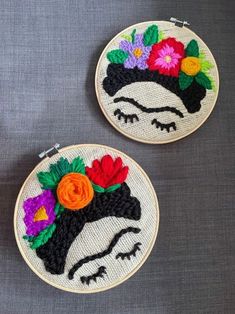 two embroidered hoops with flowers on them sitting next to each other in front of a gray background