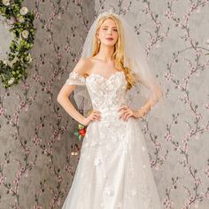 a woman in a wedding dress standing next to a wall with pink flowers on it