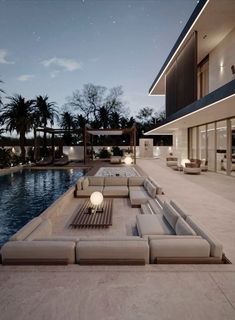 an outdoor living area with couches and tables next to a pool at night time