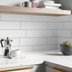 a white kitchen counter top next to a potted plant and coffee cup on the counter