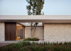 an exterior view of a modern home with trees and shrubs in the foreground,