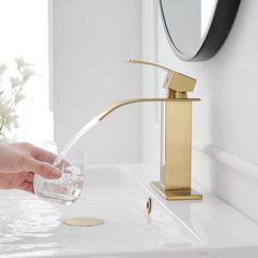 a person's hand is pouring water from a faucet into a glass