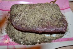 a piece of meat with seasoning on it sitting on a pink and white plate