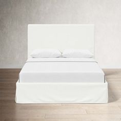 a white bed sitting on top of a hard wood floor