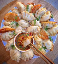 some dumplings are on a plate with chopsticks next to it and sauce in a bowl