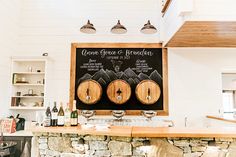 a bar with three wooden barrels on it and a chalkboard sign above the bar