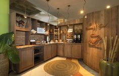 a large kitchen with wooden cabinets and green walls is pictured in this image, there are plants on the floor