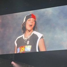 a woman standing on top of a stage in front of a screen with an image of herself