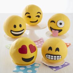 there are four yellow emoticions on the table and one is sticking its tongue out