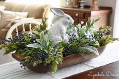 a white rabbit sitting on top of a wooden bowl filled with plants