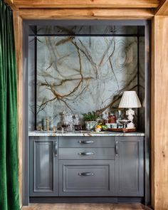 a kitchen with marble counter tops and green curtains on the wall behind it is a bar