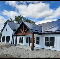 a white house with a metal roof and blue tining on the top of it