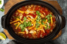 a crock pot filled with chicken tortilla soup and garnished with cilantro