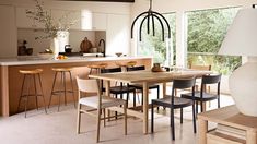 a dining room table surrounded by chairs and stools in front of a large window