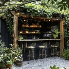 an outdoor bar with stools and potted plants on the outside, surrounded by greenery