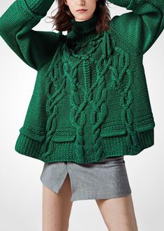 a woman is wearing a green sweater and posing for the camera with her hands on her head