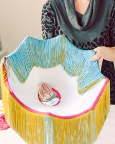 a woman is decorating a cake with colorful icing and fringes on it