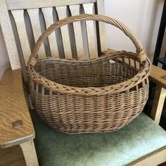 a wicker basket sitting on top of a wooden chair next to a green cushion