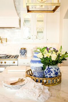 a blue and white vase sitting on top of a kitchen counter next to a plate