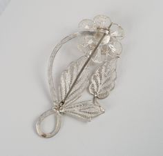 "Silver Cannetille Filigree Flower Stem Leaves Brooch Art Deco Flair to an Ancient Art, Excellent cond., 2-3/8\" H x 1-1/4\" W Roll Over Clasp. This Piece is missing the little tab which is usually attached to the back with the silver content. The piece is no less than .850 silver. The swirl of the stem with the contrast to the intricate 3D articulated leaves, petals, and stamens. The fineness of the work is incredibly beautiful. c. 1930's Please read all descriptions and view all photos careful Flower Shaped Wedding Brooches Hallmarked, Wedding Flower Brooch Hallmarked, Wedding Flower Brooches Hallmarked, Flower Shaped Wedding Brooches, Art Nouveau Wedding Brooches Hallmarked, Art Nouveau Filigree Brooch For Collectors, Collectible Art Nouveau Filigree Brooches, Art Nouveau Wedding Brooches With Filigree, Antique Flower Brooches For Wedding