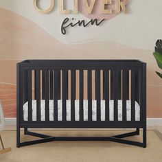 a baby crib in front of a wall with the name oliver finn on it