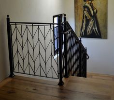 a painting hangs on the wall next to an iron railing and wooden flooring area