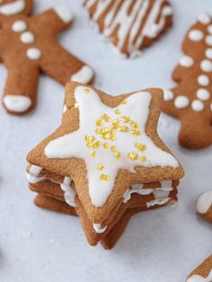 gingerbread cookies with white icing and gold sprinkles are arranged on a table