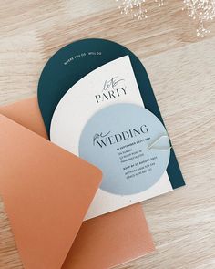 the wedding card is laying on top of two envelopes, which are both peach and green