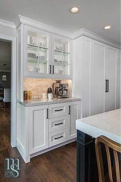 a kitchen with white cabinets and wood flooring, along with a dining room table