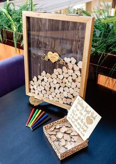 a wooden box filled with lots of wood chips next to a card board and markers