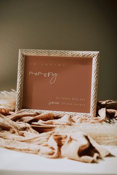 a pink wedding sign sitting on top of a bed next to a pile of blankets