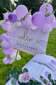 a welcome sign with purple balloons and greenery