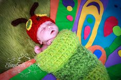 a baby sleeping in a green blanket with a red hat on it's head