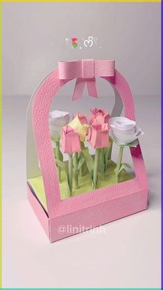 an origami box with flowers in it and a bow on the top that is pink