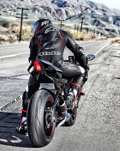 a man riding on the back of a motorcycle down a road