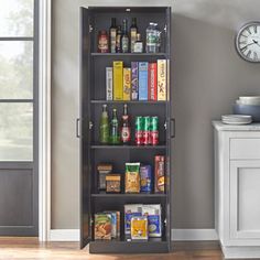 a tall bookcase filled with lots of books next to a wall mounted clock in a living room