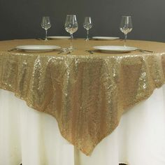 a gold table cloth with white plates and wine glasses on it, set up for a formal function