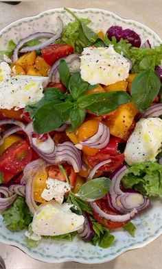 a salad with tomatoes, onions, cheese and lettuce on a white plate