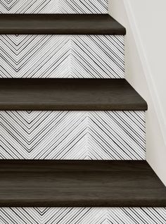 the stairs are painted white and black with herringbones on them, along with a chevroned wallpaper pattern