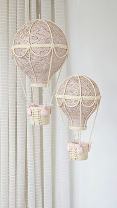 two hot air balloons hanging from the ceiling in front of curtained windows with white drapes