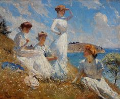 the three women are sitting on the grass by the water and one woman is standing