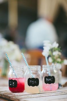 three mason jars filled with different colored liquid and straws on top of a wooden table