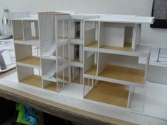 a model of a house is shown on a table next to some bookshelves