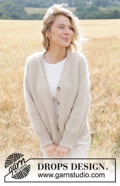 a woman standing in a field wearing a cardigan